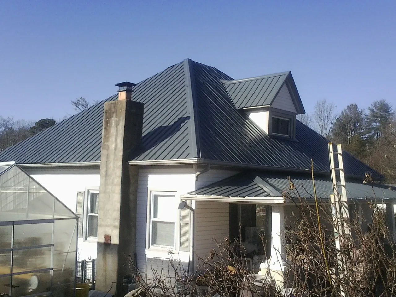 Dark blue standing seam metal roof on a white farmhouse with dormer — Slate & Tile Roof Repair by Roofing Brothers in Sudbury