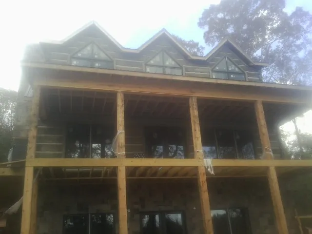 Dormers and porch framing on a large log home under construction — Roof Coating work by our crew in Sudbury