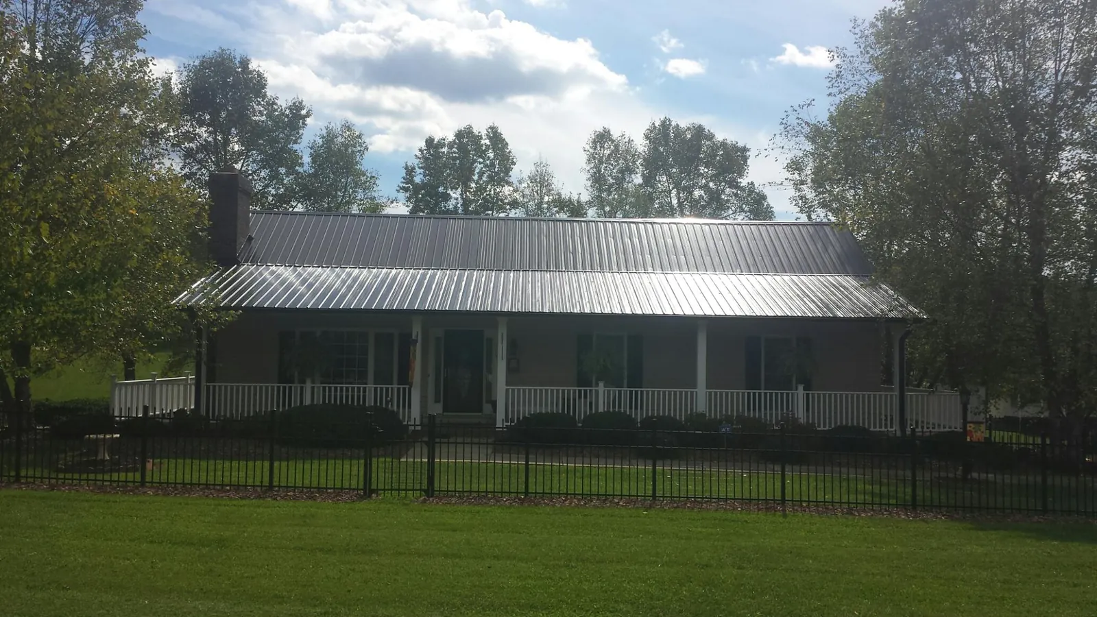 Gray metal roof on a brick ranch with a full width front porch — Gutter Guard Installation work by our crew in Sudbury