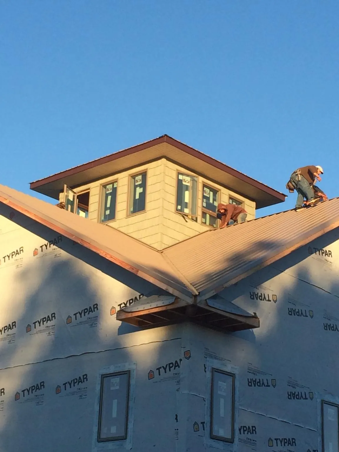 Roofers working around a rooftop cupola on a new metal roof at sunset — Roof Waterproofing in Sudbury by Roofing Brothers